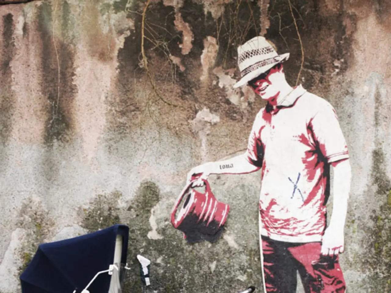 In this image there is a wall poster of a man on the wall. On the left side there is a cradle on...