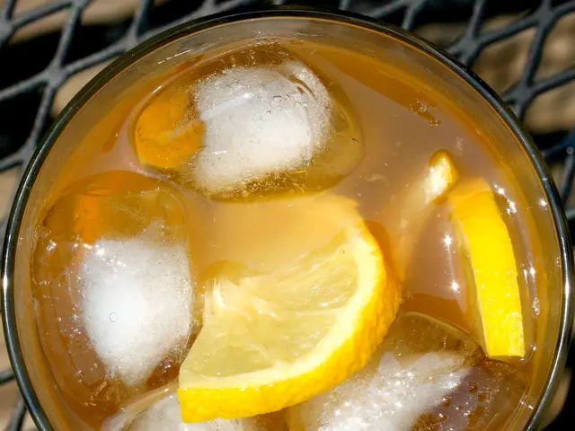 In the image there is a bowl with ice cubes,lemon slices in it on a metal table.